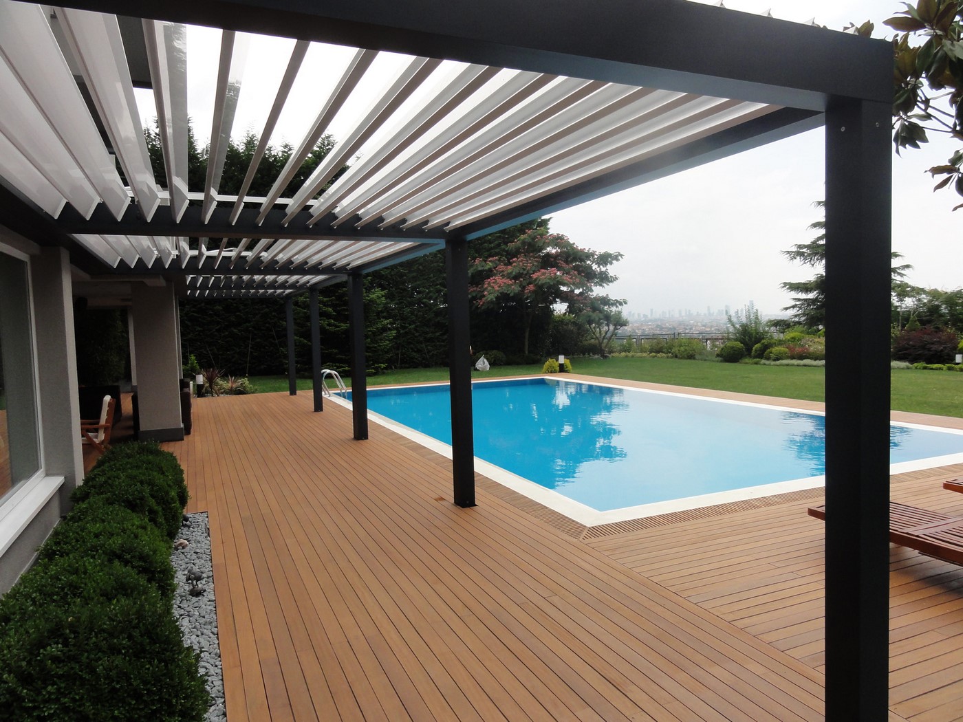 large wooden patio with a huge pool and garden